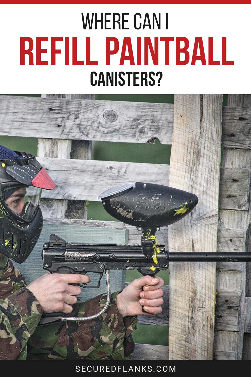 Person with a paintball gun in hands near a wooden fence - Where can I refill paintball canisters?